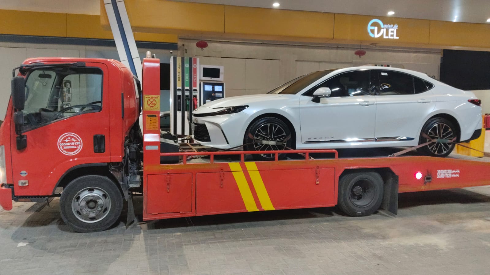 سطحة حمراء تنقل سيارة كامري في محطة وقود بجدة